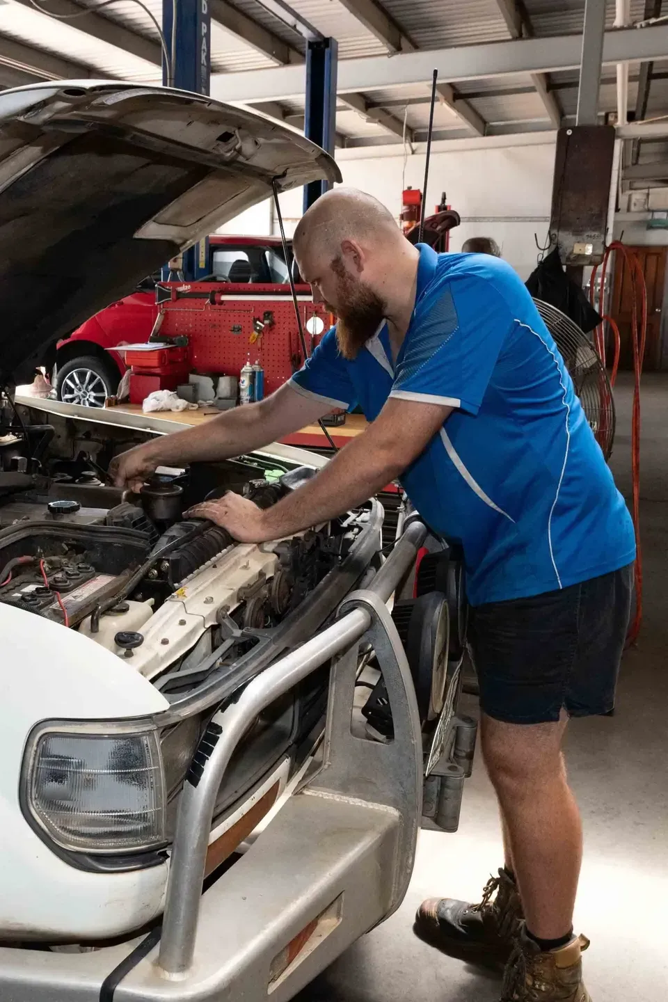 A Man is Working on a Car in a Garage With the Hood Open — Bob Parkes Automotive in Hyde Park, QLD