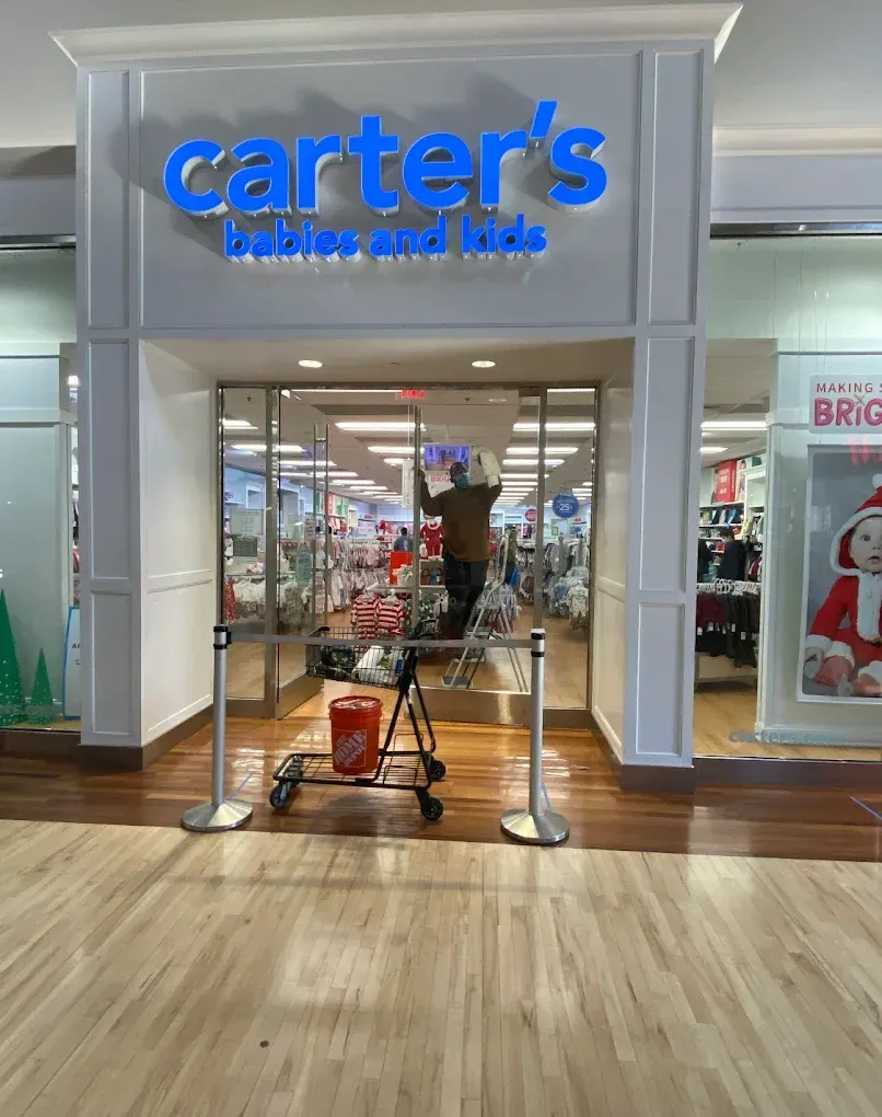 Carter's store entrance with a worker inside. A wheelchair is in front of the doors. Storefront in a mall.