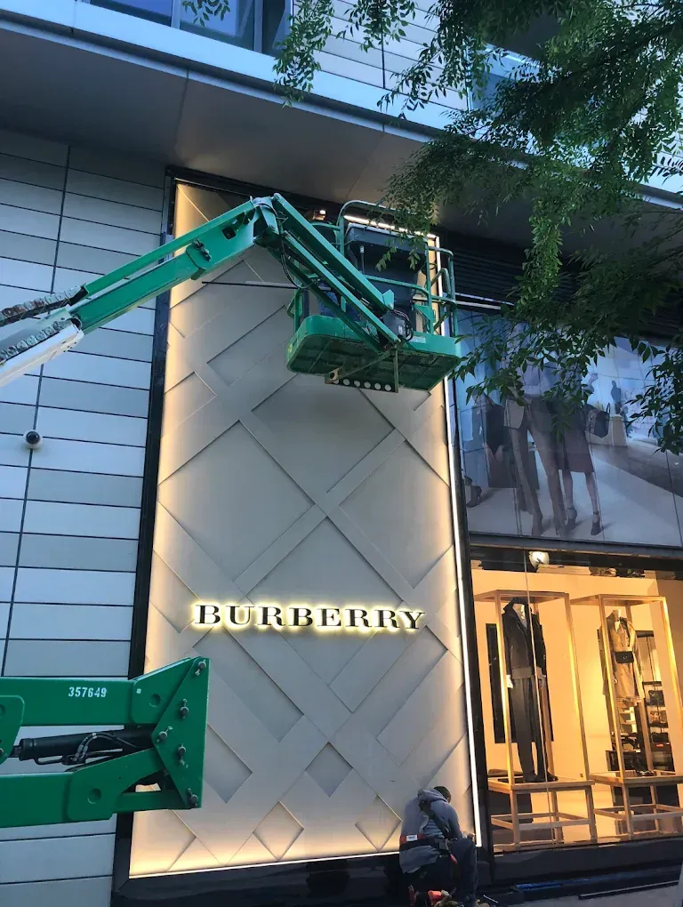Burberry store with workers on a lift, installing or maintaining sign.