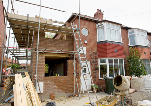 A house is being remodeled with scaffolding and a ladder.