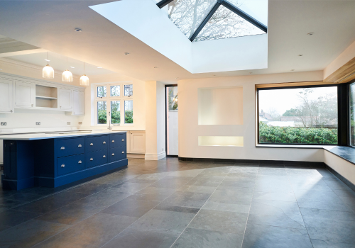 An empty kitchen with a blue island and a large window.