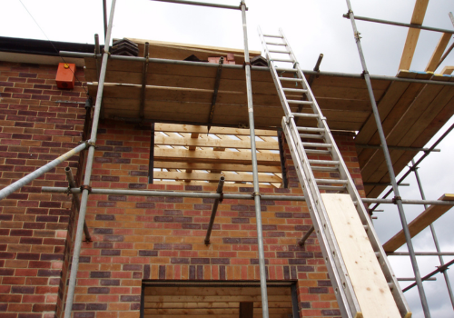A brick building under construction with scaffolding and a ladder