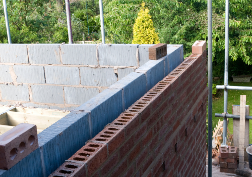 A brick wall is being built on a construction site