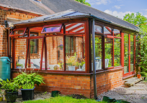 A brick house with a large glass conservatory on the side of it.