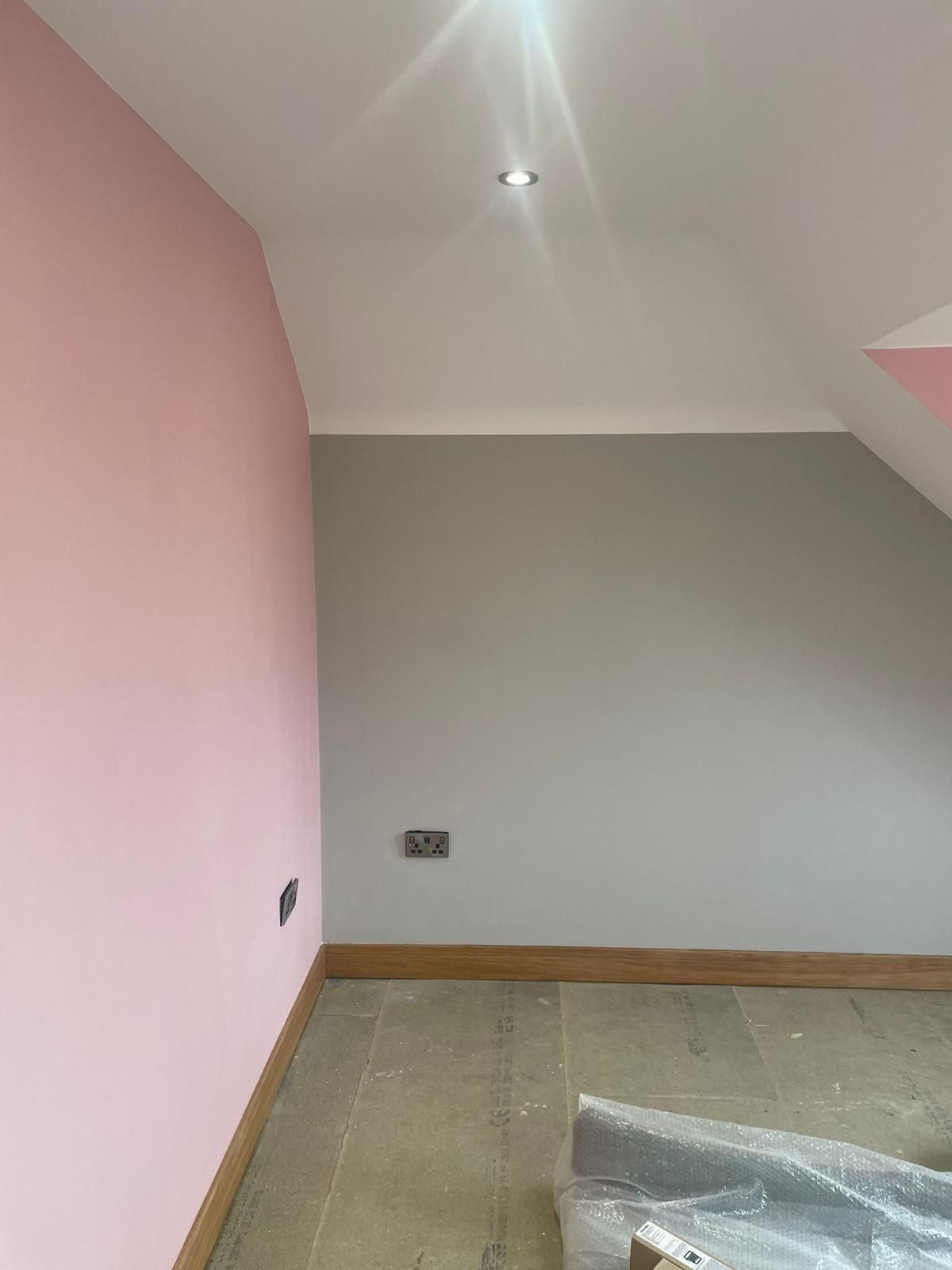 A plastered room with pink walls and a white ceiling.