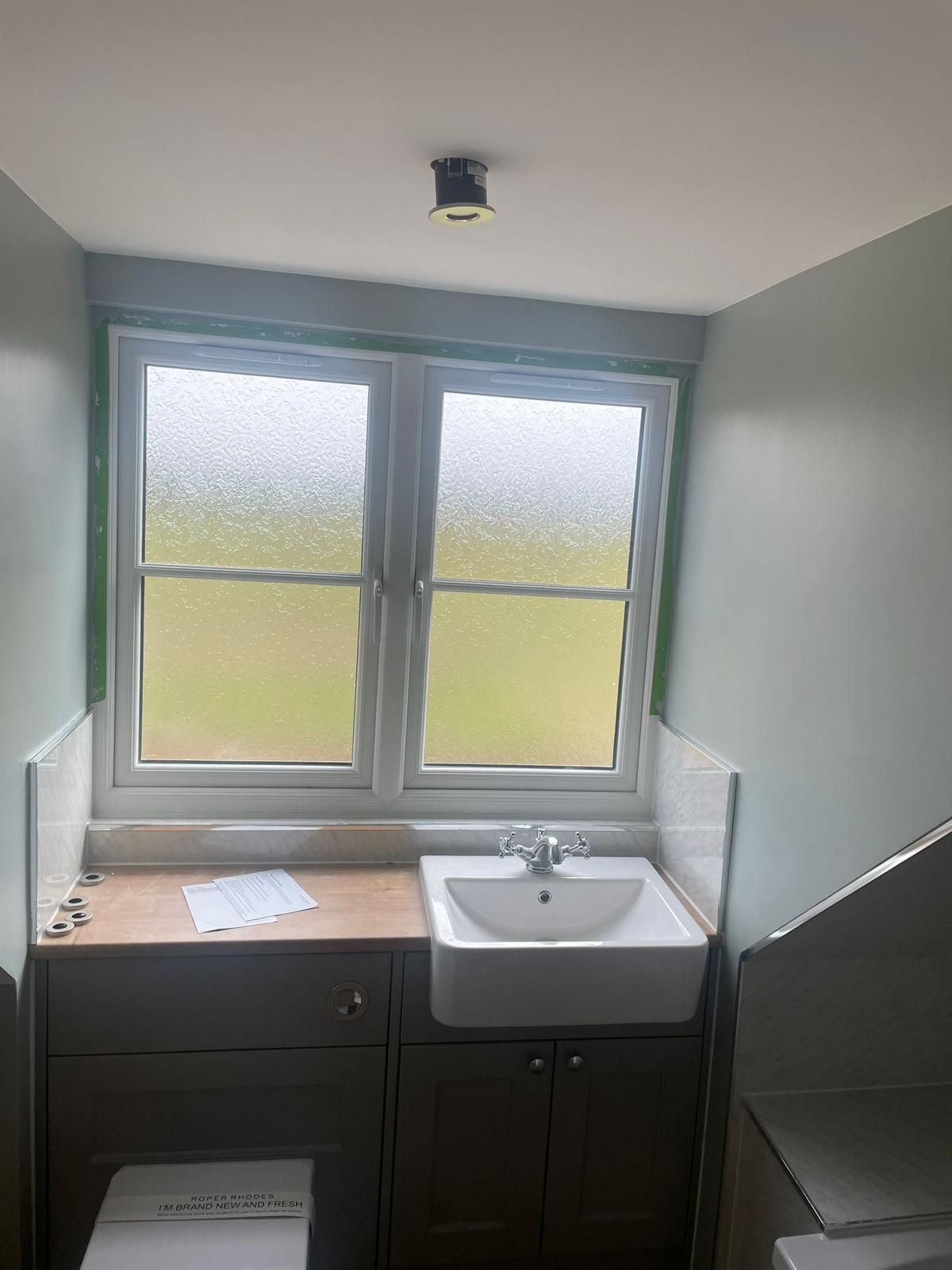 A bathroom with a sink , toilet , and window.