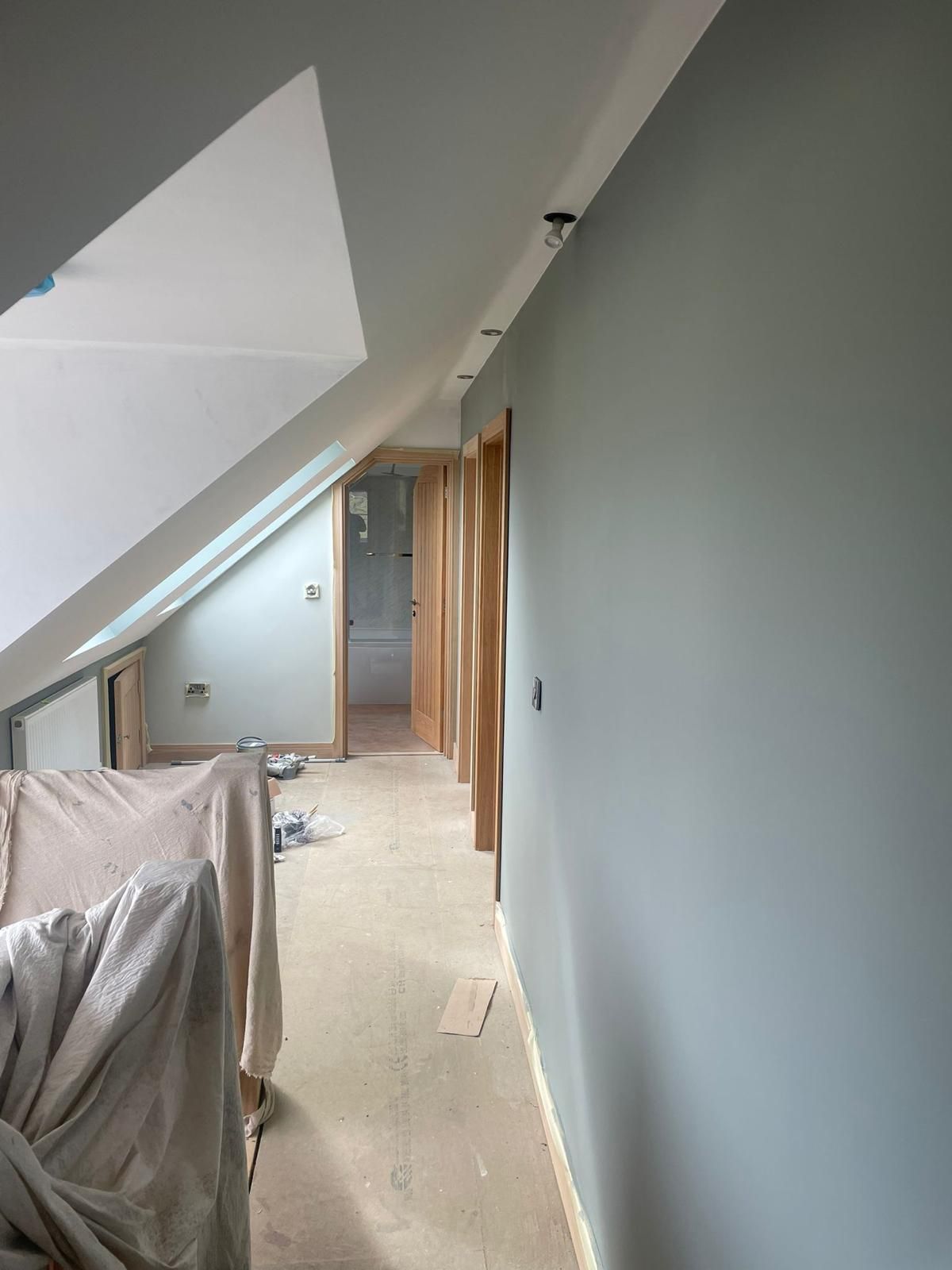 A hallway with a couch and a window in a house under construction.