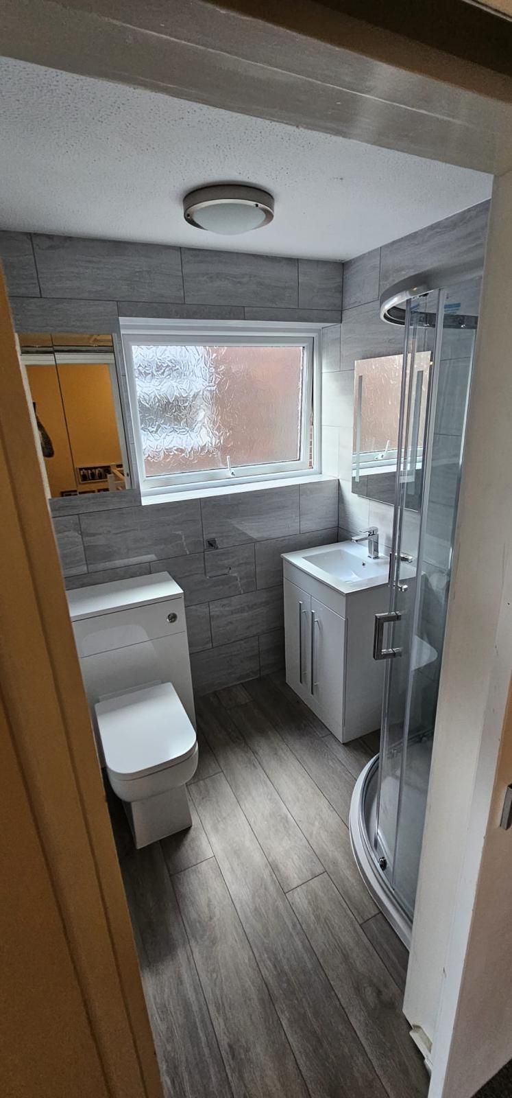 A bathroom with a toilet , sink and shower.