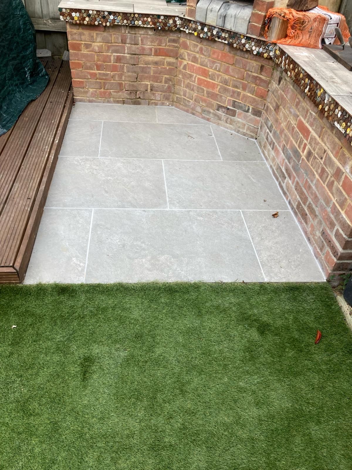 There is a brick wall in the background and a lawn in the foreground.