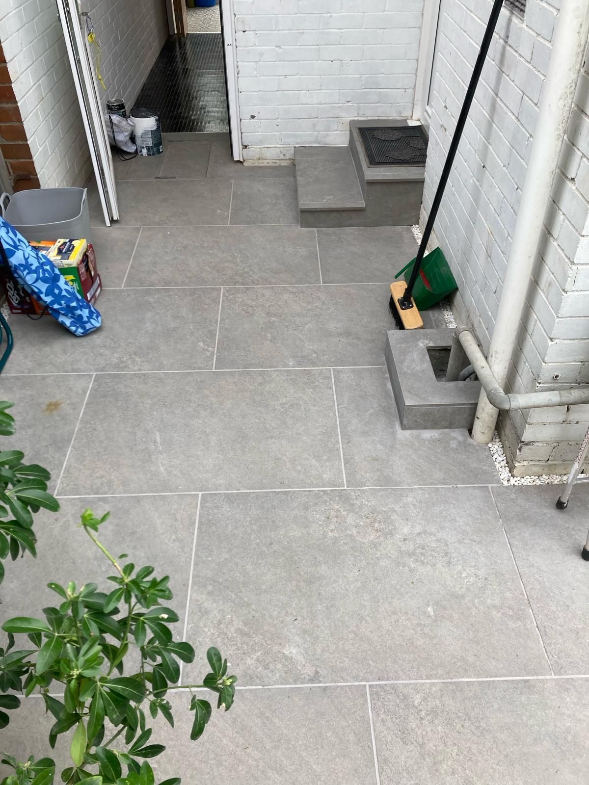 A broom is sitting on a tiled floor next to a brick wall.