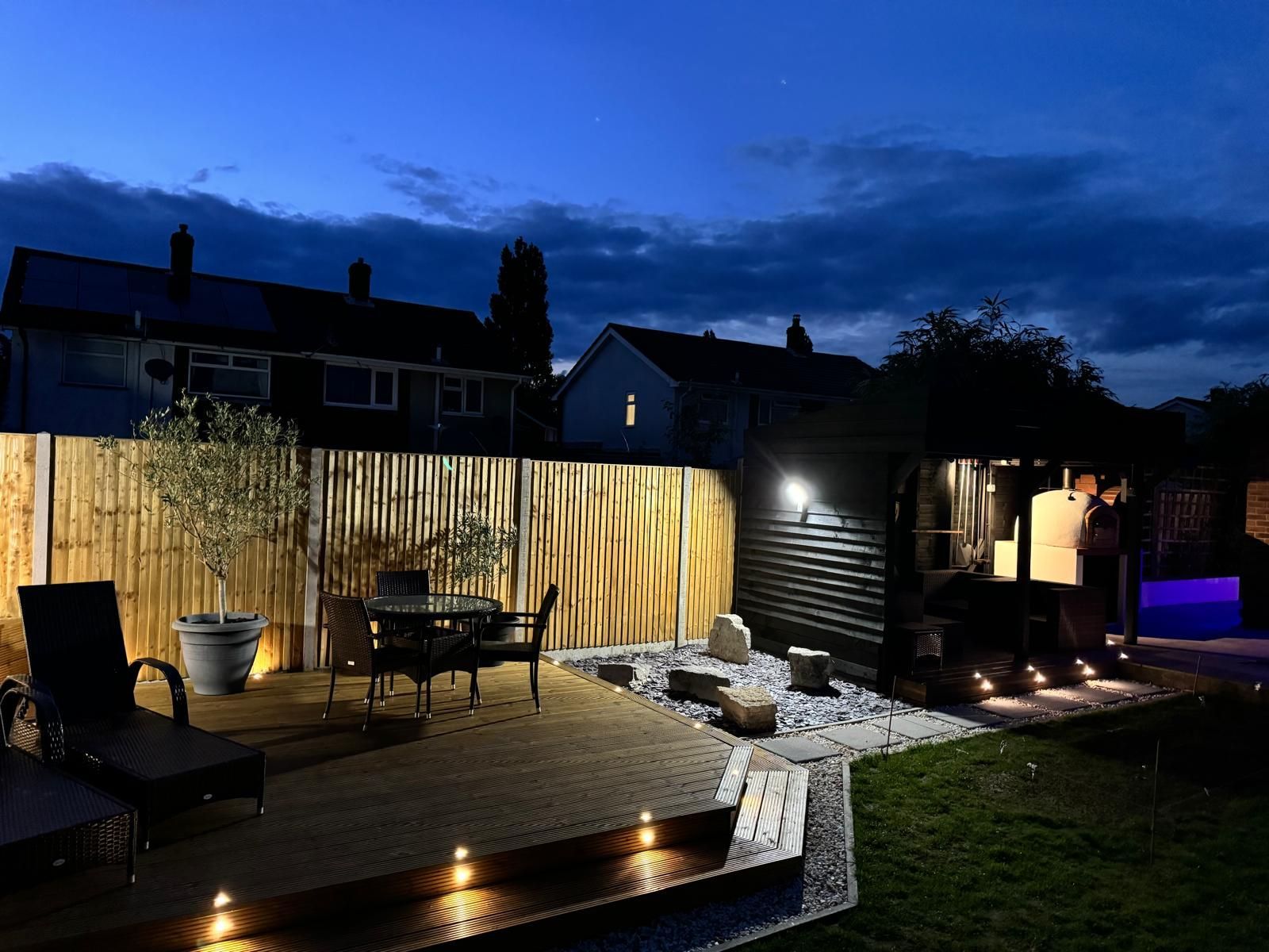 A patio with a table and chairs is lit up at night.