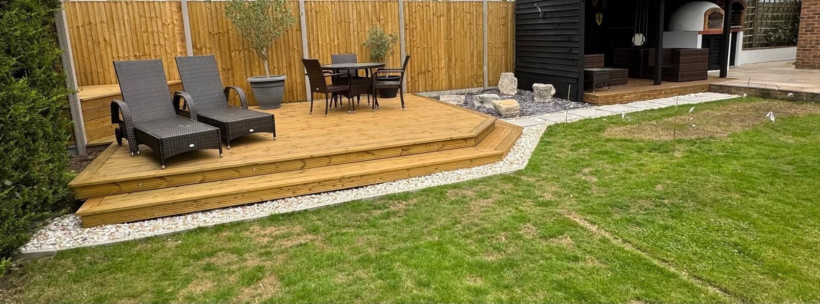 A wooden deck with chairs and a table in a backyard.