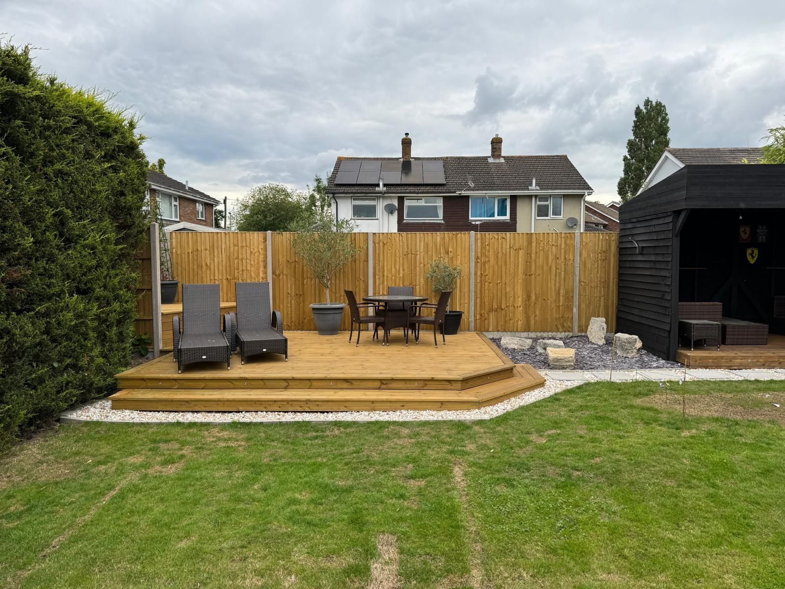 There is a wooden deck with a table and chairs in the backyard.