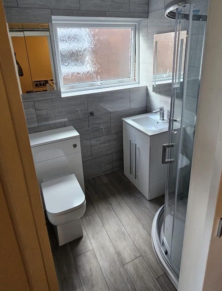 A bathroom with a toilet , sink , shower and mirror.