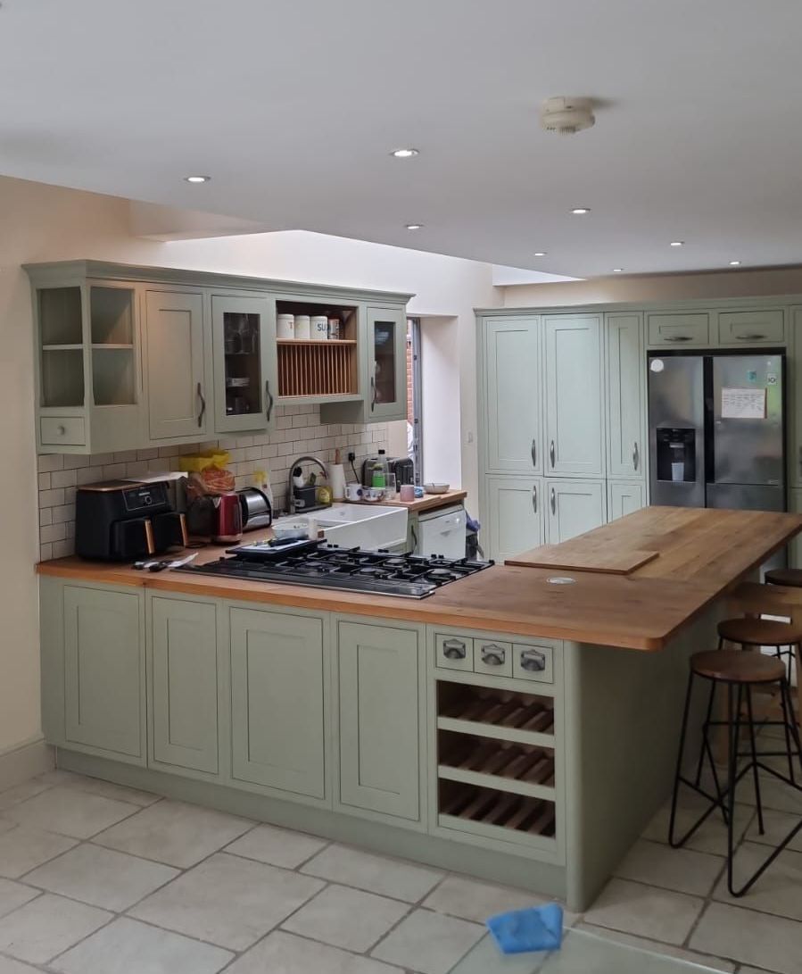 A kitchen with white cabinets , stainless steel appliances , and a large island.