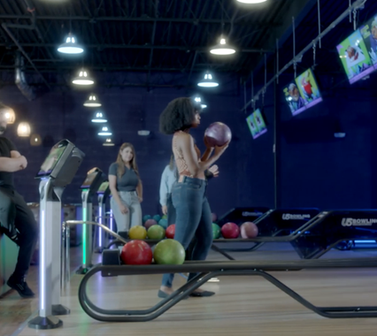 A woman is holding a bowling ball in a bowling alley
