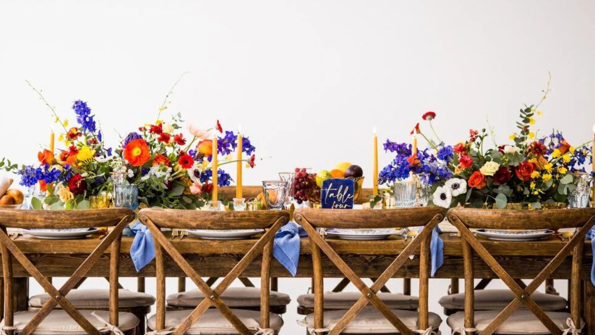 Floral funeral tributes arranged on wooden stands against a white wall