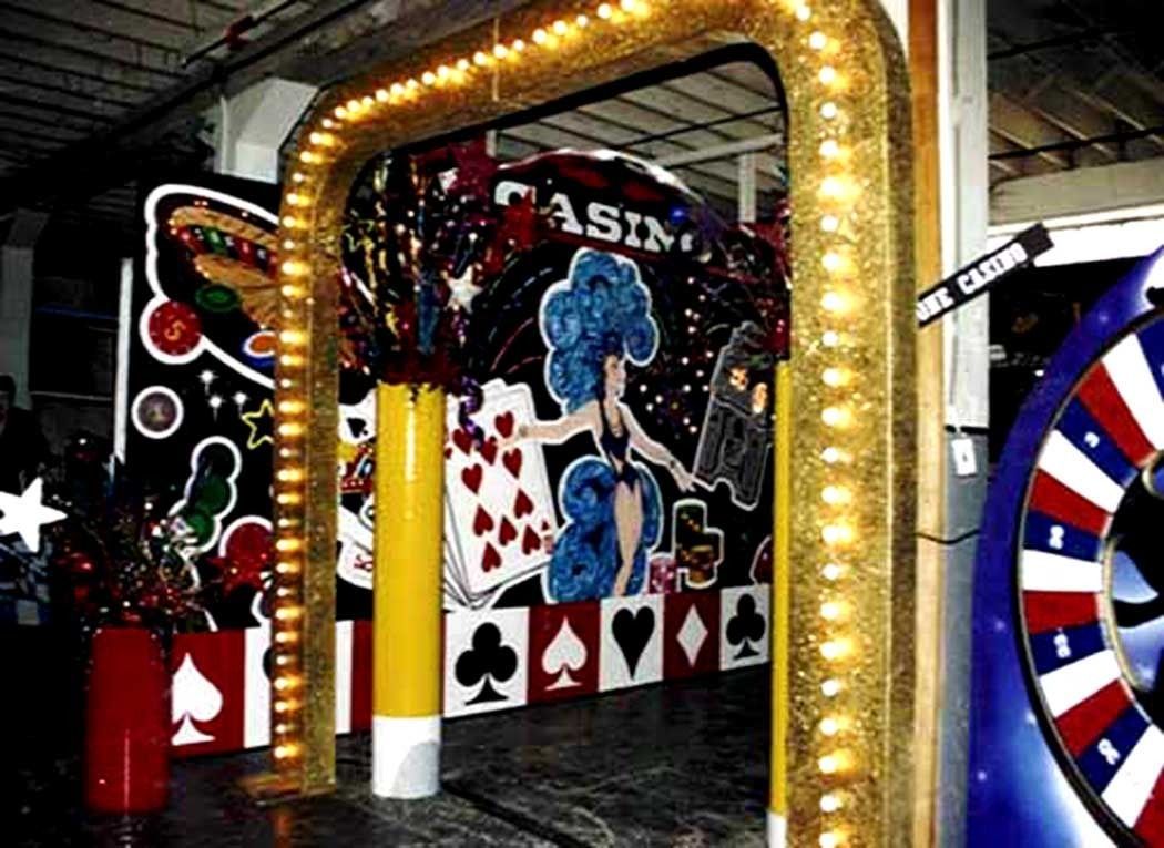 Casino-themed entrance with gold arch, playing-card wall, and roulette wheel decor