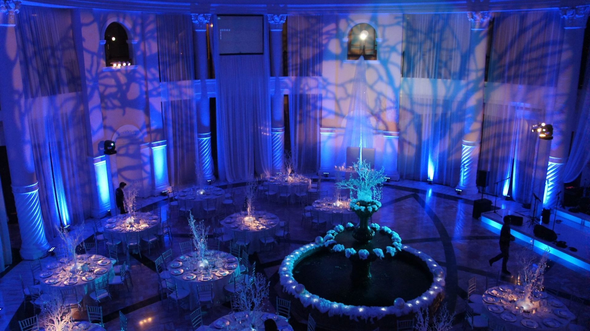 Blue-lit grand hall with arched walls, glowing fountain, and decorative crystal-like sculptures
