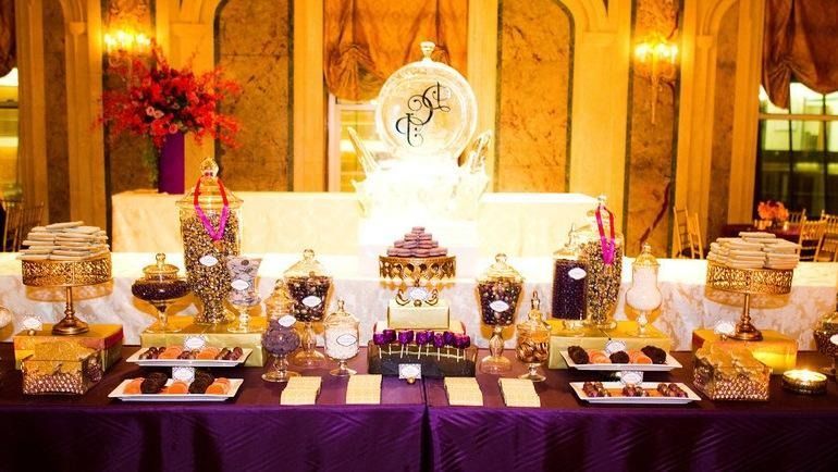 Elegant dessert buffet with cakes, pastries, and candles on a gold-lit banquet table