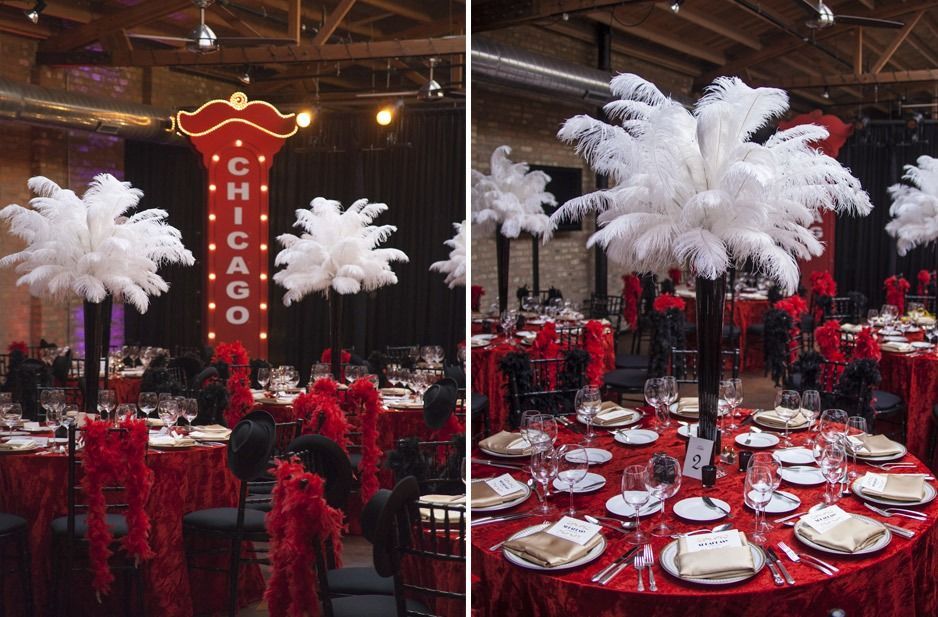 Red and black event tables with white feather centerpieces in a dimly lit banquet hall, with a CHICAGO sign.