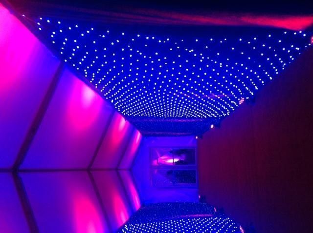 Neon-lit tunnel with blue starry ceiling and magenta walls in a futuristic hallway