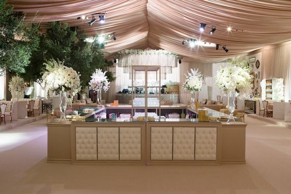 Elegant wedding reception venue with draped ceiling, floral arrangements, and a central display table