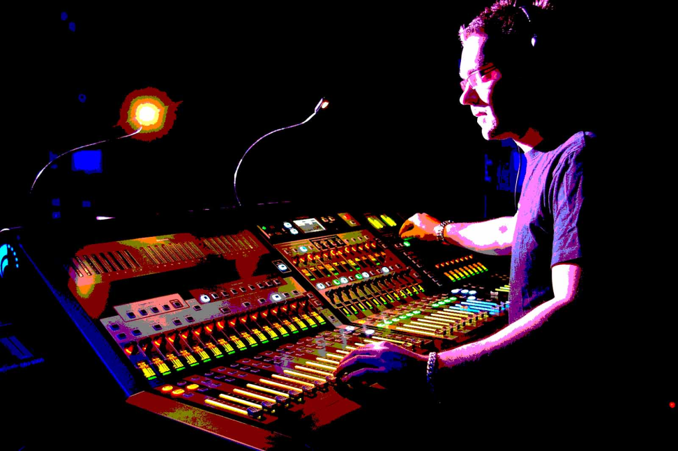 Sound engineer adjusting a colorful mixing console on a dark stage