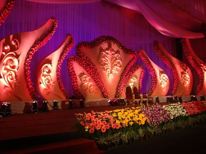 Ornate pink-lit stage with floral decorations and draped backdrop for a formal event