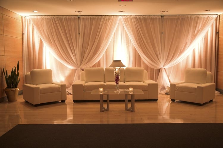 Elegant beige living room with draped curtains, sofa, armchairs, and warm ambient lighting