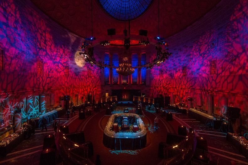 Colorfully lit cathedral interior with ornate arches, central altar, and seated audience during a performance