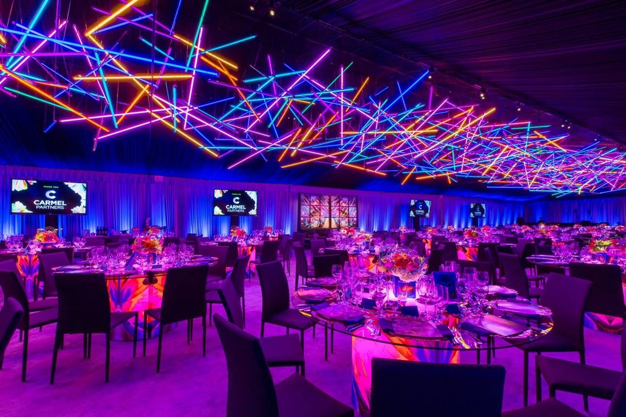 Neon-lit banquet hall with purple and blue laser ceiling lights over set dining tables and chairs