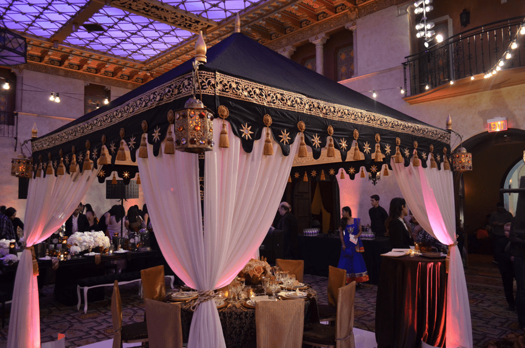 Decorated canopy tent with white drapes and black trim at an indoor event venue