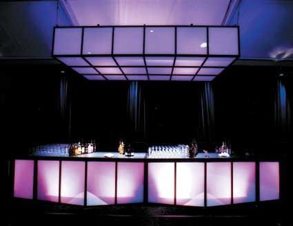 Illuminated bar with glowing pink panels and purple overhead lights in a dark venue