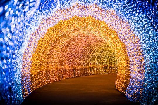 Glowing tunnel of orange and blue lights curving over a dark walkway