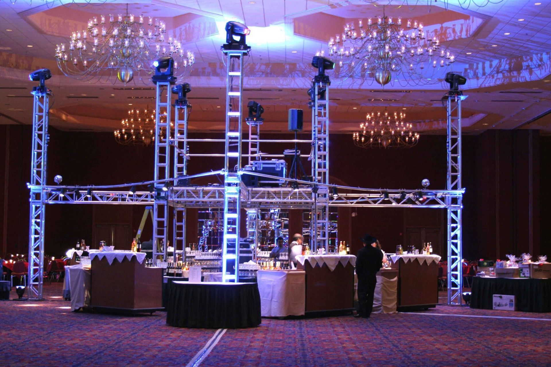 Large banquet hall with a lit stage and metal truss rigging for an event setup