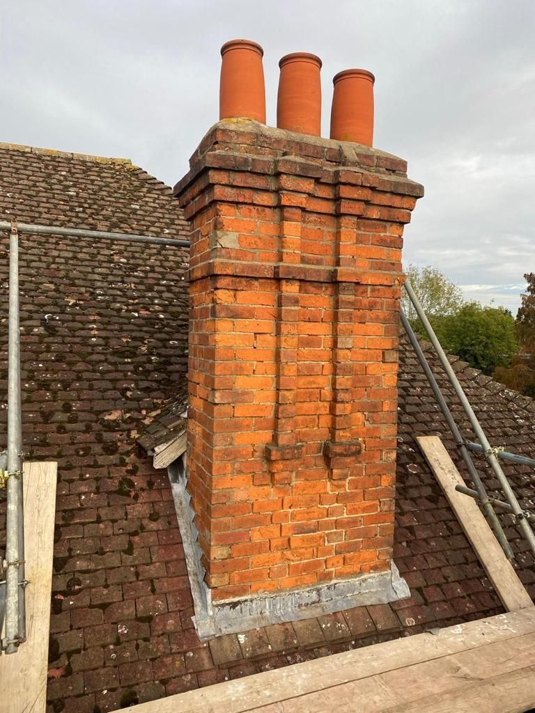 A brick chimney is sitting on top of a brick roof.