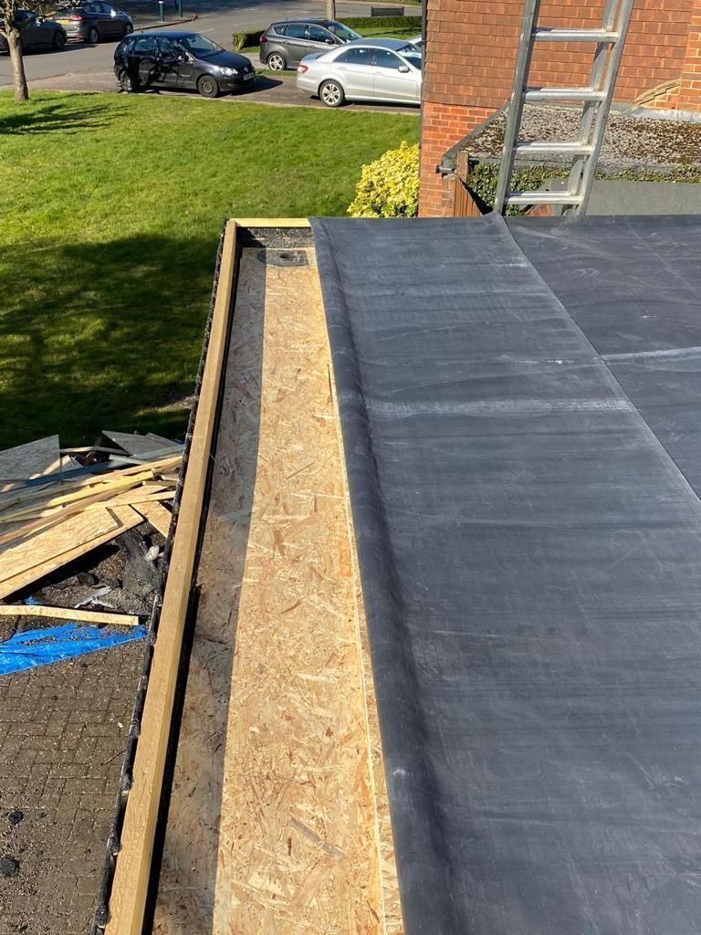 A black roof is being built on top of a brick building.