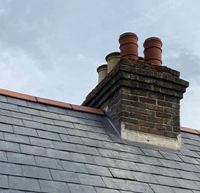 a brick chimney on top of a slate roof .