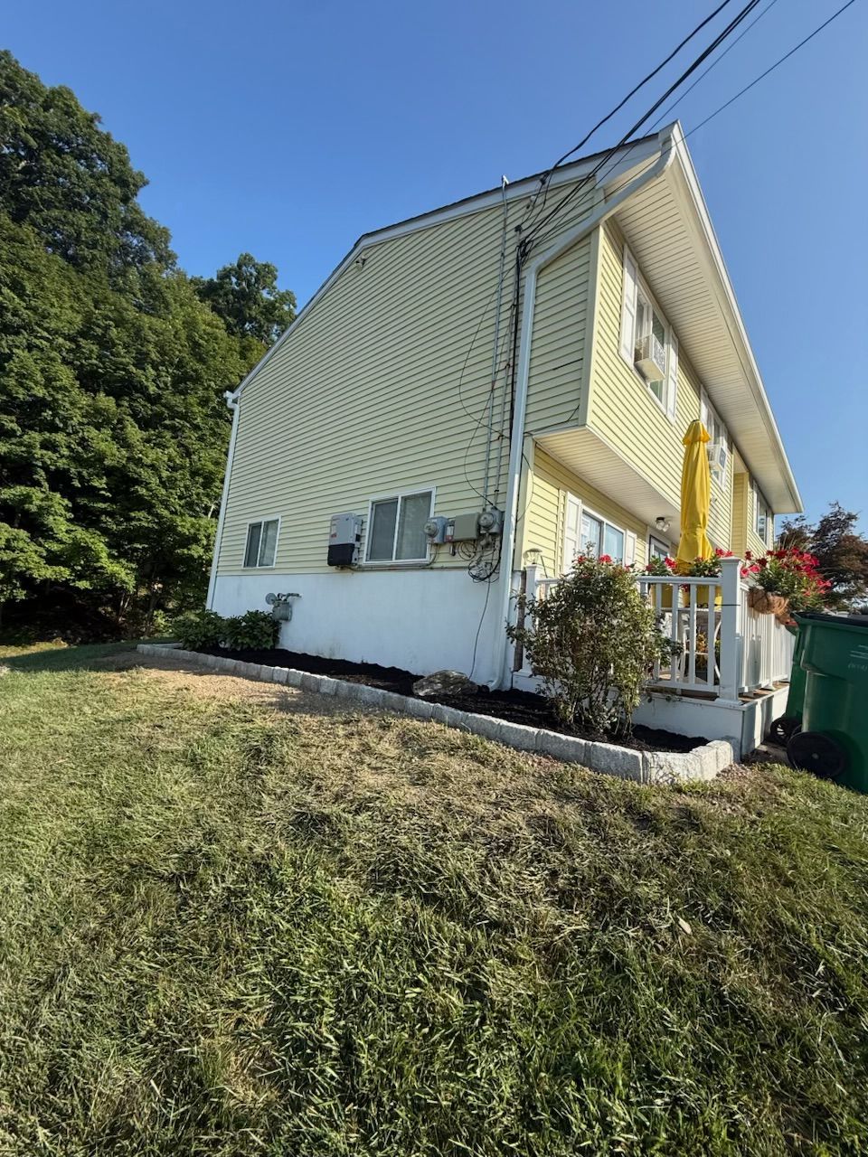 Yellow house with white trim, green grass, blue sky.