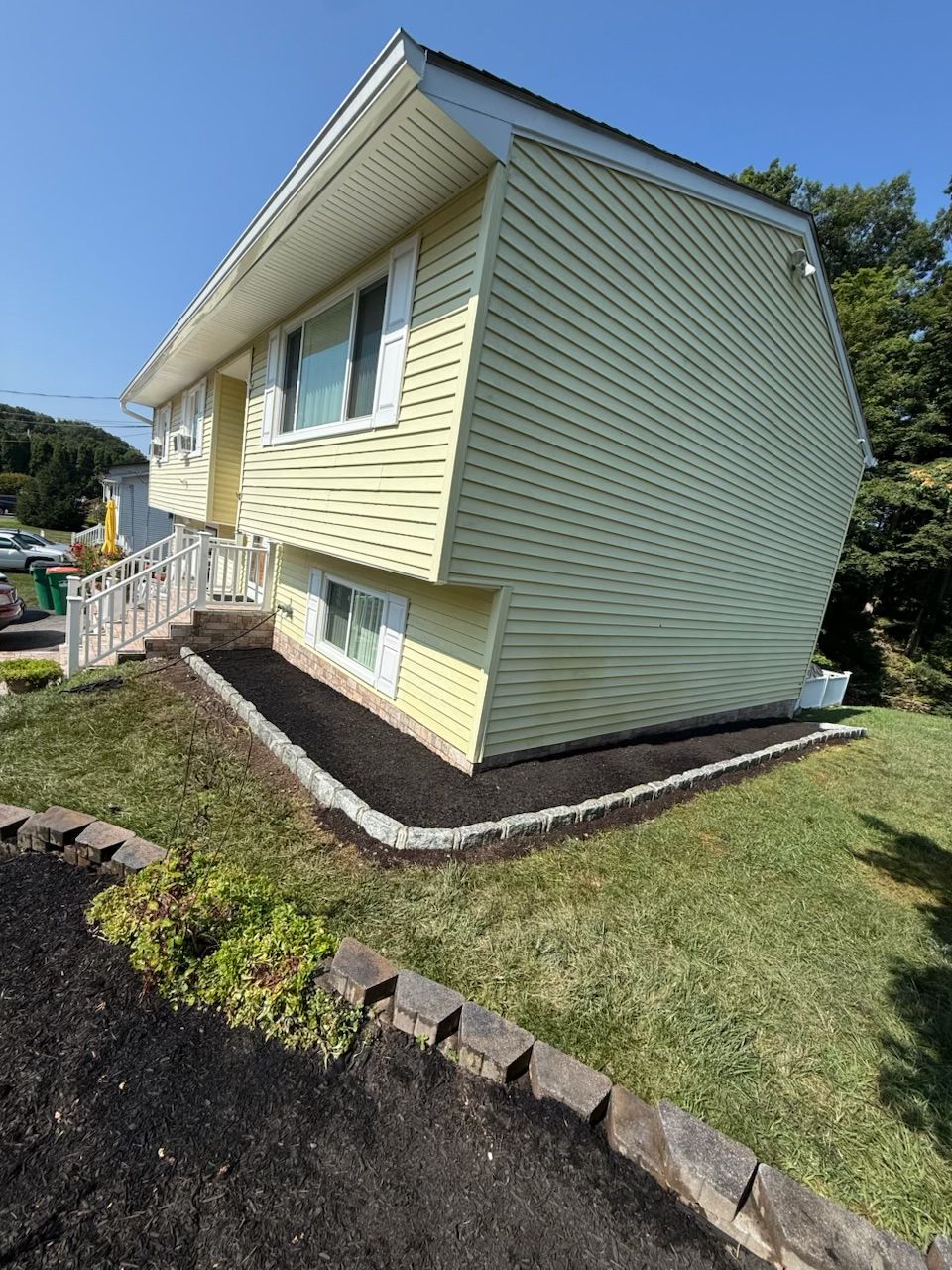 Yellow house with white trim and a neatly landscaped yard.