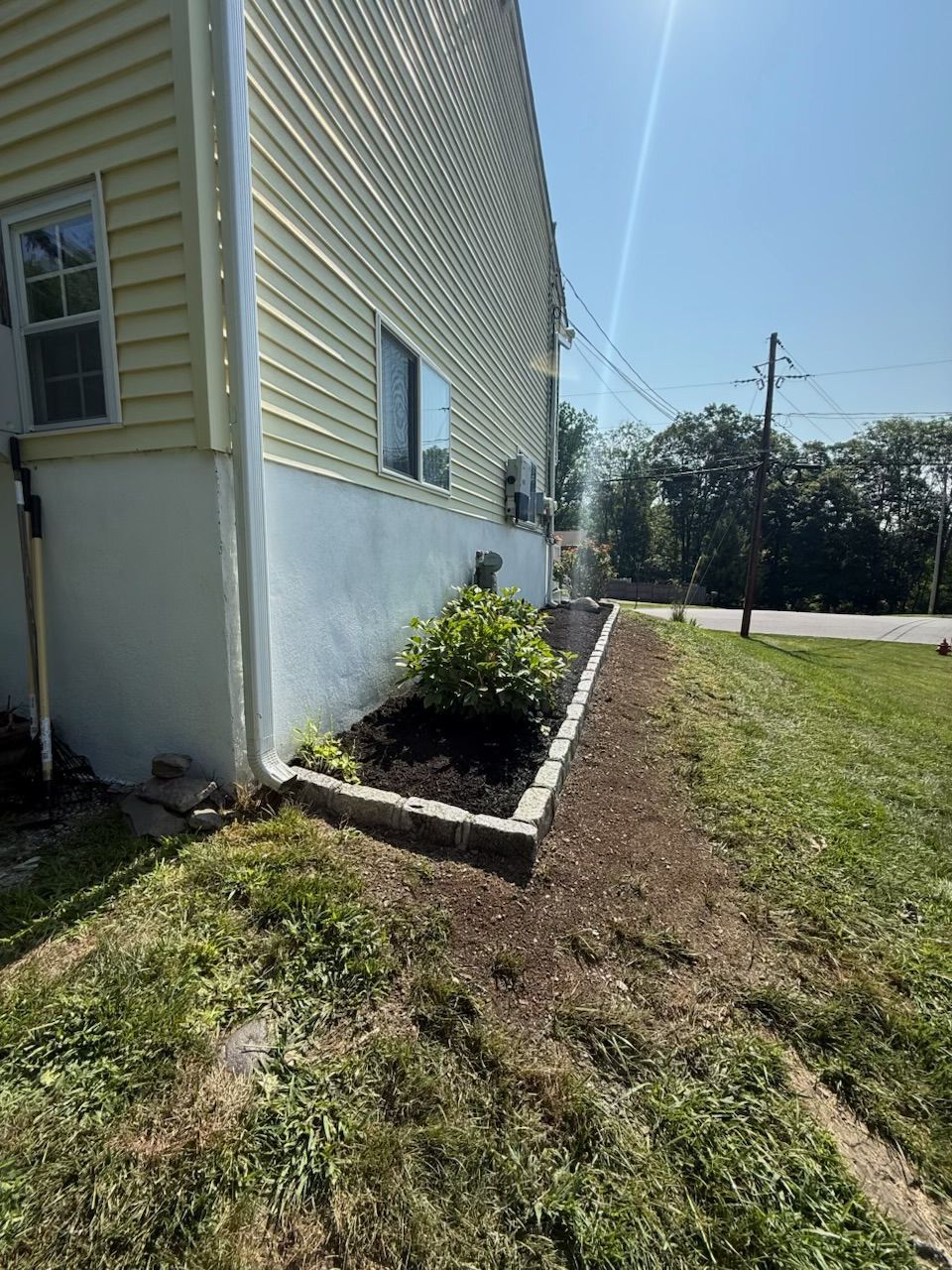 A house with a landscaped garden bed along the side on a sunny day.