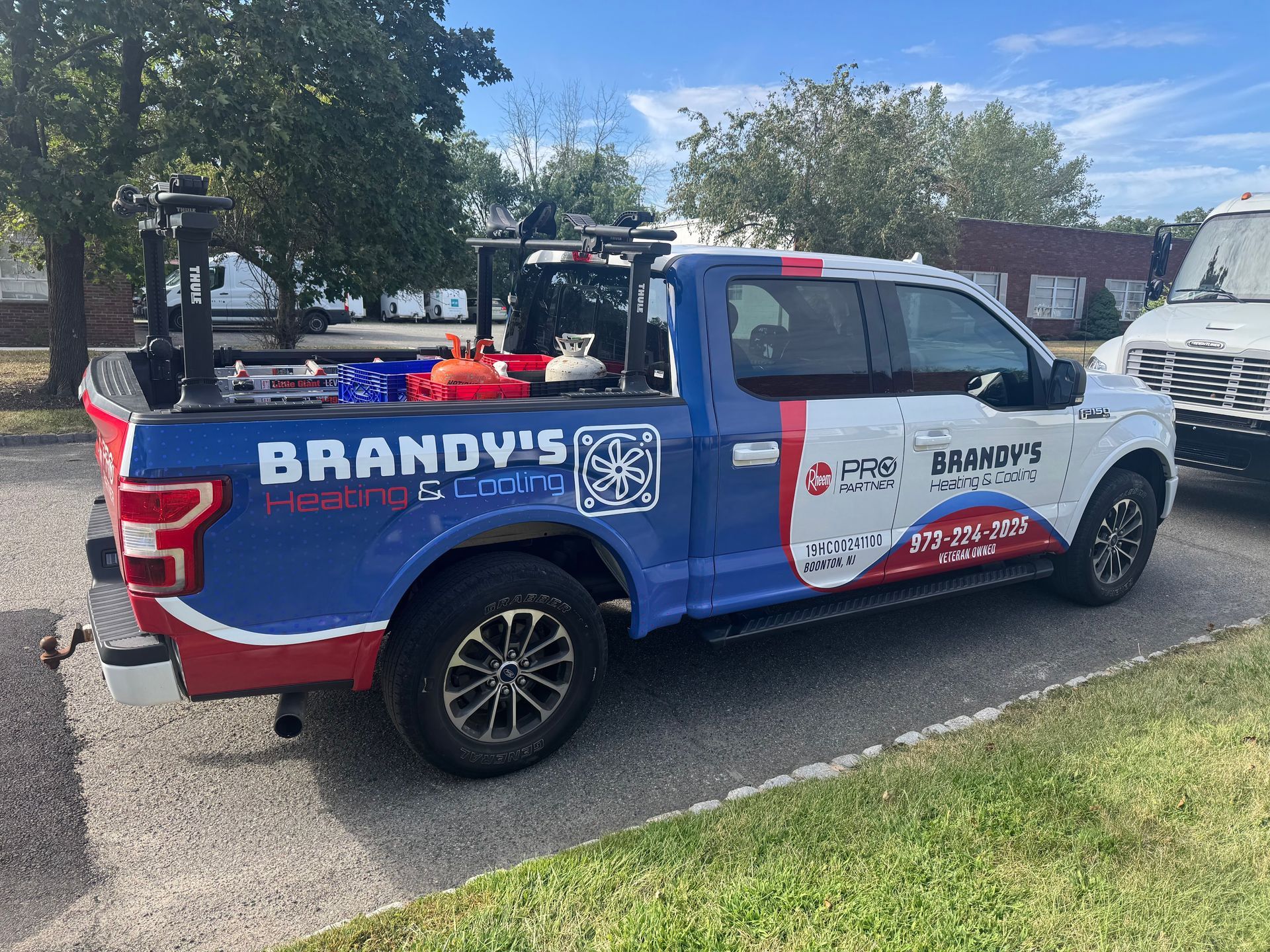 Brandy's repair truck parked on a street; red, white, and blue wrap; equipment in the bed; cloudy sky.