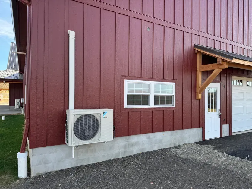Red barn exterior with white air conditioner unit and window.