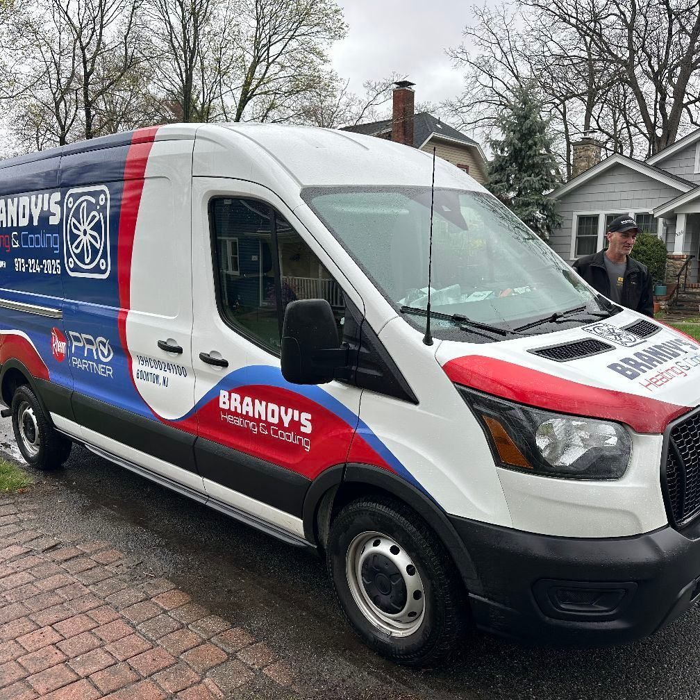 Brandy's HVAC van parked on a street. White, red, and blue logo on the van. A person stands nearby.
