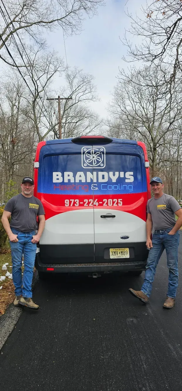 Two men stand in front of a van that reads 
