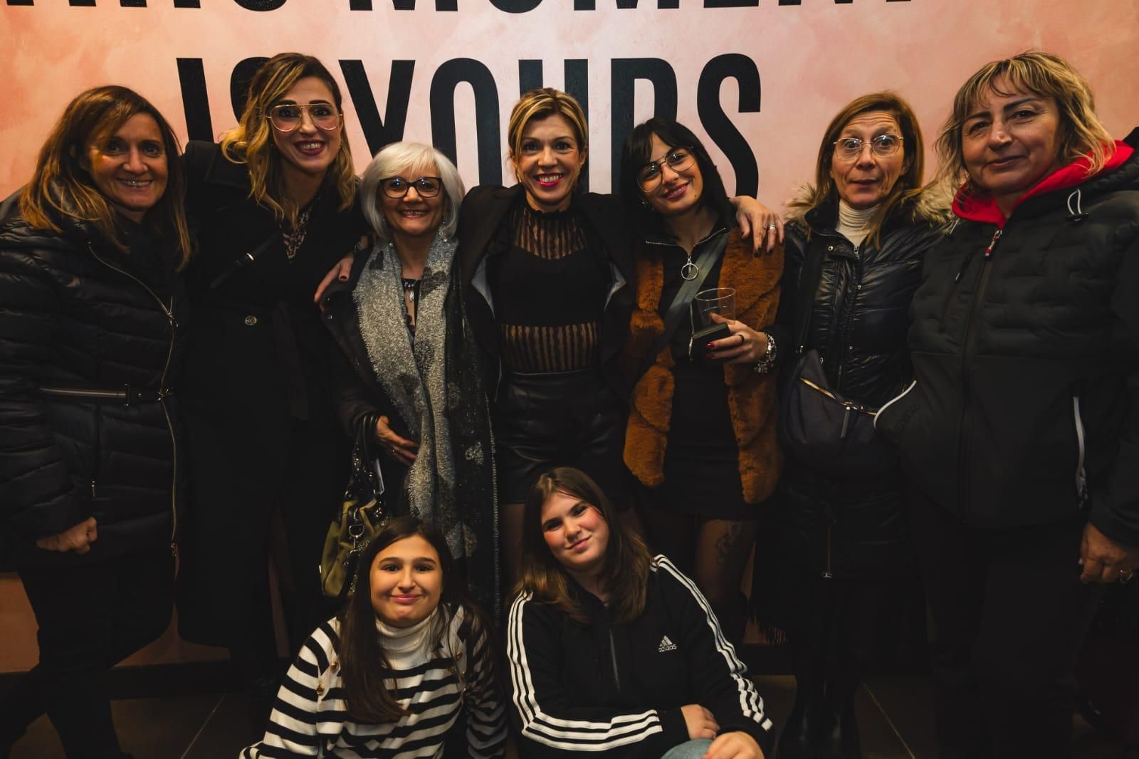 Un gruppo di donne posa per una foto davanti a un cartello che dice il tuo