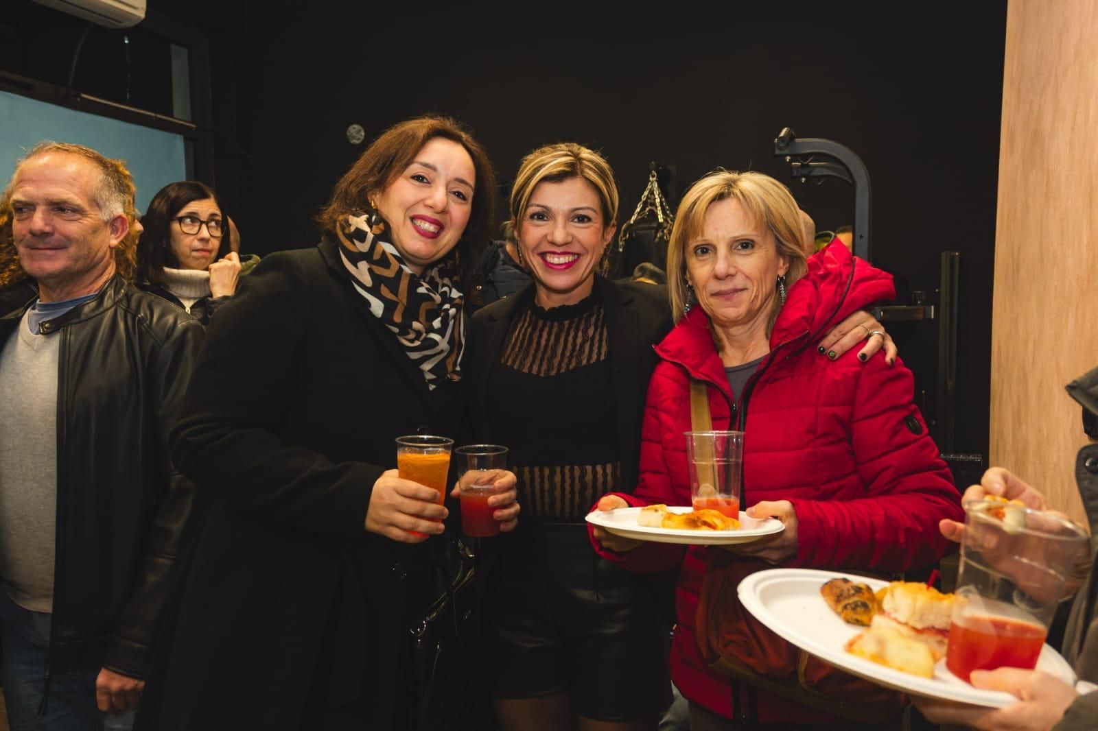 Un gruppo di donne posa per una foto mentre tengono in mano piatti di cibo.