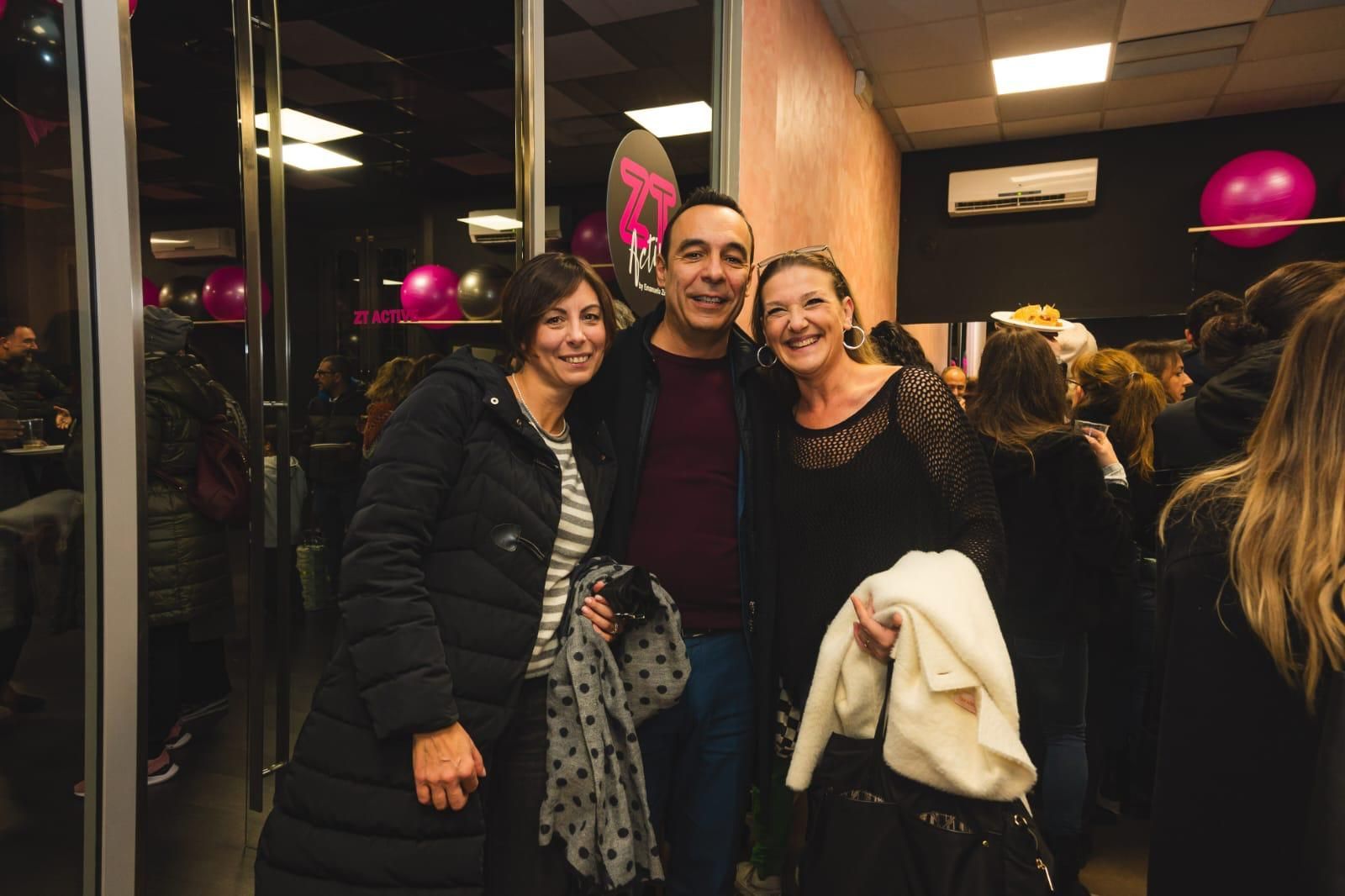 Un uomo e due donne posano per una foto in una stanza affollata.