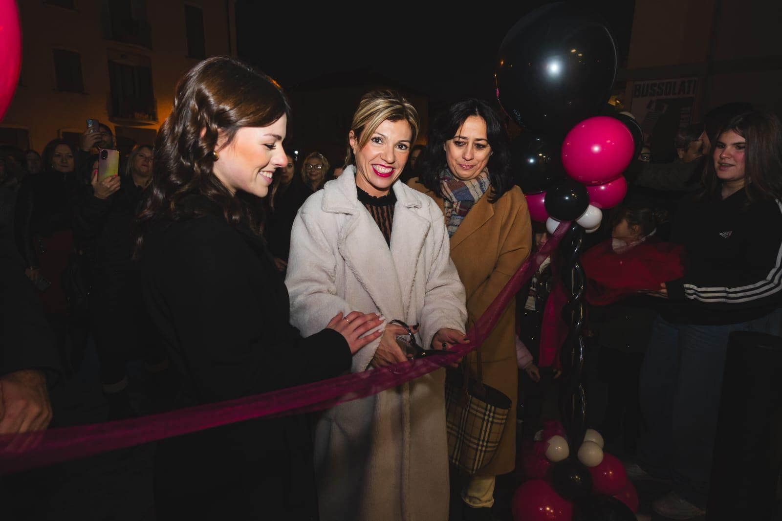 Un gruppo di donne sta tagliando un nastro a una festa.